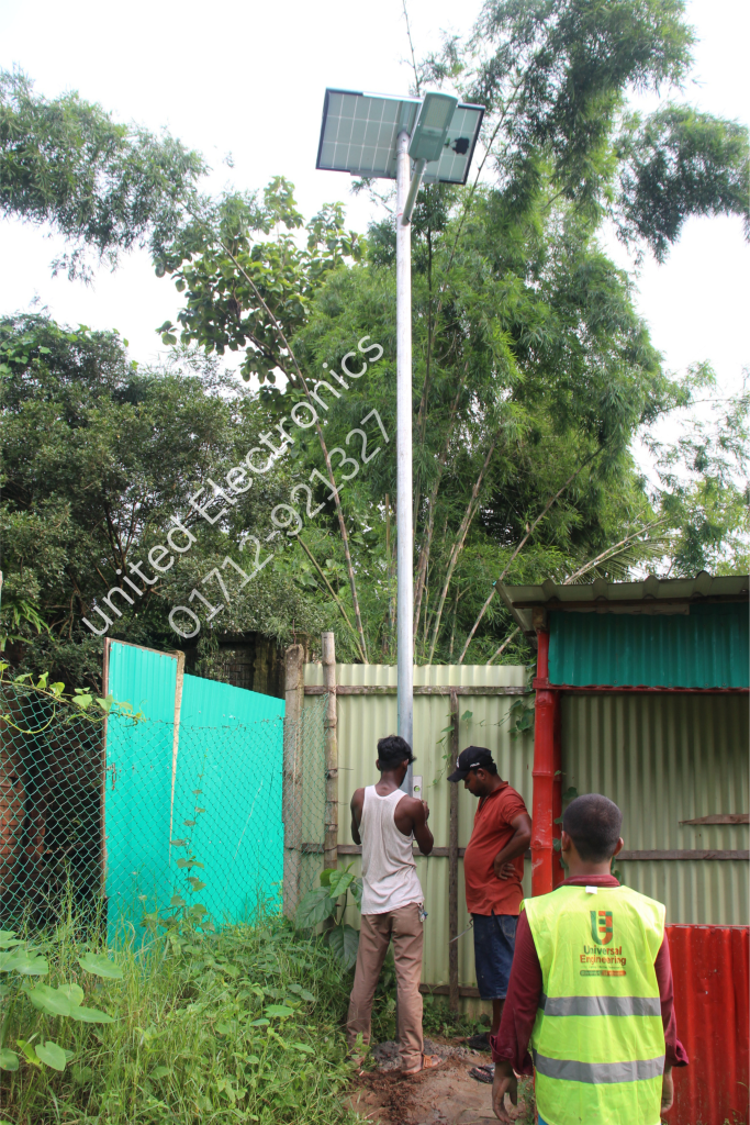 Workers beside a solar street light and panel at a compound entrance